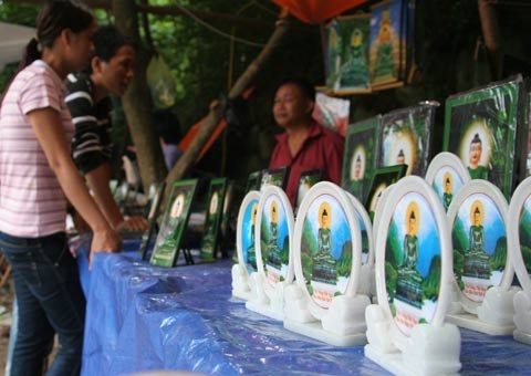 Tượng Phật ngọc tọa lạc trên đài sen trong ngôi chùa cổ miền Bắc. Hai ngày sau khi mở cửa tự do để người dân chiêm bái tượng Phật ngọc, lượng người kéo đến đây vẫn khá đông. Dù lượng người đến xem đông nhưng theo anh thanh niên này, ảnh tượng Phật ngọc bán không đắt hàng. "Xuống giá 10.000 đồng một ảnh to một ảnh nhỏ nhưng cũng chẳng mấy người mua. Từ sáng tới giờ tôi mới bán được chừng 300 tấm", người này nói. Tương tự, các cửa hàng bán tranh tượng Phật in trên gỗ, ảnh tượng Phật in trên đá... cũng ế ẩm. Trong khi đó, một công ty chuyên kinh doanh quà tặng đã chép nguyên mẫu tượng Phật ngọc để đúc lại với kích cỡ nhỏ hơn. Dù không phải làm thủ công mà được đúc bằng bột đá nhưng giá một bức tượng cao chừng 50 cm là 5 triệu đồng, còn bức tượng nhỏ bằng bàn tay giá 300.000 đồng. Loại tượng đặc biệt này đã thu hút sự chú ý của người xem. Tuy nhiên, nhiều người cũng chỉ dám cầm lên xem rồi đặt xuống... ... hay chụp bức ảnh làm kỷ niệm, thay vì chụp bức ảnh Phật ngọc nguyên mẫu được đặt ở quá xa. Dịch vụ chụp ảnh lấy ngay trong 5 phút cũng khá hút khách vì ai cũng muốn có một bức hình làm kỷ niệm nhân dịp tận mắt ngắm bức tượng Phật ngọc lớn nhất thế giới. Còn ở ngoài đường, mỗi khi có ôtô chở khách xịch đỗ là hàng chục người dân đi xe máy chạy tới mời đi xe ôm giá 10.000 - 15.000 đồng một lượt cho quãng đường 5-6 km. Nếu không đi xe ôm, du khách sẽ phải đi bộ vài km mới tới được nơi bày tượng Phật. Tượng Phật ngọc tọa lạc trên đài sen trong ngôi chùa cổ miền Bắc. Hai ngày sau khi mở cửa tự do để người dân chiêm bái tượng Phật ngọc, lượng người kéo đến đây vẫn khá đông. Dù lượng người đến xem đông nhưng theo anh thanh niên này, ảnh tượng Phật ngọc bán không đắt hàng. "Xuống giá 10.000 đồng một ảnh to một ảnh nhỏ nhưng cũng chẳng mấy người mua. Từ sáng tới giờ tôi mới bán được chừng 300 tấm", người này nói. Tương tự, các cửa hàng bán tranh tượng Phật in trên gỗ, ảnh tượng Phật in trên đá... cũng ế ẩm. Trong khi đó, một công ty chuyên kinh doanh quà tặng đã chép nguyên mẫu tượng Phật ngọc để đúc lại với kích cỡ nhỏ hơn. Dù không phải làm thủ công mà được đúc bằng bột đá nhưng giá một bức tượng cao chừng 50 cm là 5 triệu đồng, còn bức tượng nhỏ bằng bàn tay giá 300.000 đồng. Loại tượng đặc biệt này đã thu hút sự chú ý của người xem. Tuy nhiên, nhiều người cũng chỉ dám cầm lên xem rồi đặt xuống... ... hay chụp bức ảnh làm kỷ niệm, thay vì chụp bức ảnh Phật ngọc nguyên mẫu được đặt ở quá xa. Dịch vụ chụp ảnh lấy ngay trong 5 phút cũng khá hút khách vì ai cũng muốn có một bức hình làm kỷ niệm nhân dịp tận mắt ngắm bức tượng Phật ngọc lớn nhất thế giới. Còn ở ngoài đường, mỗi khi có ôtô chở khách xịch đỗ là hàng chục người dân đi xe máy chạy tới mời đi xe ôm giá 10.000 - 15.000 đồng một lượt cho quãng đường 5-6 km. Nếu không đi xe ôm, du khách sẽ phải đi bộ vài km mới tới được nơi bày tượng Phật.