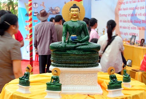 Tượng Phật ngọc tọa lạc trên đài sen trong ngôi chùa cổ miền Bắc. Hai ngày sau khi mở cửa tự do để người dân chiêm bái tượng Phật ngọc, lượng người kéo đến đây vẫn khá đông. Dù lượng người đến xem đông nhưng theo anh thanh niên này, ảnh tượng Phật ngọc bán không đắt hàng. "Xuống giá 10.000 đồng một ảnh to một ảnh nhỏ nhưng cũng chẳng mấy người mua. Từ sáng tới giờ tôi mới bán được chừng 300 tấm", người này nói. Tương tự, các cửa hàng bán tranh tượng Phật in trên gỗ, ảnh tượng Phật in trên đá... cũng ế ẩm. Trong khi đó, một công ty chuyên kinh doanh quà tặng đã chép nguyên mẫu tượng Phật ngọc để đúc lại với kích cỡ nhỏ hơn. Dù không phải làm thủ công mà được đúc bằng bột đá nhưng giá một bức tượng cao chừng 50 cm là 5 triệu đồng, còn bức tượng nhỏ bằng bàn tay giá 300.000 đồng. Loại tượng đặc biệt này đã thu hút sự chú ý của người xem. Tuy nhiên, nhiều người cũng chỉ dám cầm lên xem rồi đặt xuống... ... hay chụp bức ảnh làm kỷ niệm, thay vì chụp bức ảnh Phật ngọc nguyên mẫu được đặt ở quá xa. Dịch vụ chụp ảnh lấy ngay trong 5 phút cũng khá hút khách vì ai cũng muốn có một bức hình làm kỷ niệm nhân dịp tận mắt ngắm bức tượng Phật ngọc lớn nhất thế giới. Còn ở ngoài đường, mỗi khi có ôtô chở khách xịch đỗ là hàng chục người dân đi xe máy chạy tới mời đi xe ôm giá 10.000 - 15.000 đồng một lượt cho quãng đường 5-6 km. Nếu không đi xe ôm, du khách sẽ phải đi bộ vài km mới tới được nơi bày tượng Phật. Tượng Phật ngọc tọa lạc trên đài sen trong ngôi chùa cổ miền Bắc. Hai ngày sau khi mở cửa tự do để người dân chiêm bái tượng Phật ngọc, lượng người kéo đến đây vẫn khá đông. Dù lượng người đến xem đông nhưng theo anh thanh niên này, ảnh tượng Phật ngọc bán không đắt hàng. "Xuống giá 10.000 đồng một ảnh to một ảnh nhỏ nhưng cũng chẳng mấy người mua. Từ sáng tới giờ tôi mới bán được chừng 300 tấm", người này nói. Tương tự, các cửa hàng bán tranh tượng Phật in trên gỗ, ảnh tượng Phật in trên đá... cũng ế ẩm. Trong khi đó, một công ty chuyên kinh doanh quà tặng đã chép nguyên mẫu tượng Phật ngọc để đúc lại với kích cỡ nhỏ hơn. Dù không phải làm thủ công mà được đúc bằng bột đá nhưng giá một bức tượng cao chừng 50 cm là 5 triệu đồng, còn bức tượng nhỏ bằng bàn tay giá 300.000 đồng. Loại tượng đặc biệt này đã thu hút sự chú ý của người xem. Tuy nhiên, nhiều người cũng chỉ dám cầm lên xem rồi đặt xuống... ... hay chụp bức ảnh làm kỷ niệm, thay vì chụp bức ảnh Phật ngọc nguyên mẫu được đặt ở quá xa. Dịch vụ chụp ảnh lấy ngay trong 5 phút cũng khá hút khách vì ai cũng muốn có một bức hình làm kỷ niệm nhân dịp tận mắt ngắm bức tượng Phật ngọc lớn nhất thế giới. Còn ở ngoài đường, mỗi khi có ôtô chở khách xịch đỗ là hàng chục người dân đi xe máy chạy tới mời đi xe ôm giá 10.000 - 15.000 đồng một lượt cho quãng đường 5-6 km. Nếu không đi xe ôm, du khách sẽ phải đi bộ vài km mới tới được nơi bày tượng Phật.