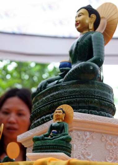 Tượng Phật ngọc tọa lạc trên đài sen trong ngôi chùa cổ miền Bắc. Hai ngày sau khi mở cửa tự do để người dân chiêm bái tượng Phật ngọc, lượng người kéo đến đây vẫn khá đông. Dù lượng người đến xem đông nhưng theo anh thanh niên này, ảnh tượng Phật ngọc bán không đắt hàng. "Xuống giá 10.000 đồng một ảnh to một ảnh nhỏ nhưng cũng chẳng mấy người mua. Từ sáng tới giờ tôi mới bán được chừng 300 tấm", người này nói. Tương tự, các cửa hàng bán tranh tượng Phật in trên gỗ, ảnh tượng Phật in trên đá... cũng ế ẩm. Trong khi đó, một công ty chuyên kinh doanh quà tặng đã chép nguyên mẫu tượng Phật ngọc để đúc lại với kích cỡ nhỏ hơn. Dù không phải làm thủ công mà được đúc bằng bột đá nhưng giá một bức tượng cao chừng 50 cm là 5 triệu đồng, còn bức tượng nhỏ bằng bàn tay giá 300.000 đồng. Loại tượng đặc biệt này đã thu hút sự chú ý của người xem. Tuy nhiên, nhiều người cũng chỉ dám cầm lên xem rồi đặt xuống... ... hay chụp bức ảnh làm kỷ niệm, thay vì chụp bức ảnh Phật ngọc nguyên mẫu được đặt ở quá xa. Dịch vụ chụp ảnh lấy ngay trong 5 phút cũng khá hút khách vì ai cũng muốn có một bức hình làm kỷ niệm nhân dịp tận mắt ngắm bức tượng Phật ngọc lớn nhất thế giới. Còn ở ngoài đường, mỗi khi có ôtô chở khách xịch đỗ là hàng chục người dân đi xe máy chạy tới mời đi xe ôm giá 10.000 - 15.000 đồng một lượt cho quãng đường 5-6 km. Nếu không đi xe ôm, du khách sẽ phải đi bộ vài km mới tới được nơi bày tượng Phật. Tượng Phật ngọc tọa lạc trên đài sen trong ngôi chùa cổ miền Bắc. Hai ngày sau khi mở cửa tự do để người dân chiêm bái tượng Phật ngọc, lượng người kéo đến đây vẫn khá đông. Dù lượng người đến xem đông nhưng theo anh thanh niên này, ảnh tượng Phật ngọc bán không đắt hàng. "Xuống giá 10.000 đồng một ảnh to một ảnh nhỏ nhưng cũng chẳng mấy người mua. Từ sáng tới giờ tôi mới bán được chừng 300 tấm", người này nói. Tương tự, các cửa hàng bán tranh tượng Phật in trên gỗ, ảnh tượng Phật in trên đá... cũng ế ẩm. Trong khi đó, một công ty chuyên kinh doanh quà tặng đã chép nguyên mẫu tượng Phật ngọc để đúc lại với kích cỡ nhỏ hơn. Dù không phải làm thủ công mà được đúc bằng bột đá nhưng giá một bức tượng cao chừng 50 cm là 5 triệu đồng, còn bức tượng nhỏ bằng bàn tay giá 300.000 đồng. Loại tượng đặc biệt này đã thu hút sự chú ý của người xem. Tuy nhiên, nhiều người cũng chỉ dám cầm lên xem rồi đặt xuống... ... hay chụp bức ảnh làm kỷ niệm, thay vì chụp bức ảnh Phật ngọc nguyên mẫu được đặt ở quá xa. Dịch vụ chụp ảnh lấy ngay trong 5 phút cũng khá hút khách vì ai cũng muốn có một bức hình làm kỷ niệm nhân dịp tận mắt ngắm bức tượng Phật ngọc lớn nhất thế giới. Còn ở ngoài đường, mỗi khi có ôtô chở khách xịch đỗ là hàng chục người dân đi xe máy chạy tới mời đi xe ôm giá 10.000 - 15.000 đồng một lượt cho quãng đường 5-6 km. Nếu không đi xe ôm, du khách sẽ phải đi bộ vài km mới tới được nơi bày tượng Phật.