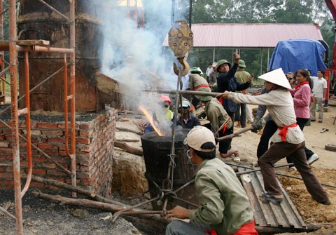 Từ sáng sớm, hàng nghìn người đã đổ về khu đúc tượng cạnh Học viện Phật giáo VN (Sóc Sơn, Hà Nội). Theo lịch âm, hôm nay là ngày "trùng cửu", ngày có ý nghĩa thiêng liêng đặc biệt, rất thích hợp để tiến hành đúc tượng Thánh Gióng - Đức Thánh Phù Đổng Thiên vương. Một mô hình thu nhỏ đặt cạnh khu đúc tượng để phật tử làm lễ, chiêm bái. Khi hoàn thành, tượng cao gần 11 m, độ vươn chéo lên trời khoảng 16 m. Rất nhiều người góp trang sức bằng kim loại quý để hòa cùng dòng đồng nóng chảy lúc đổ vào khuôn. Tại khu đất được cách ly cạnh đó, hai chiếc khuôn của phần đầu ngựa và thân trên Thánh Gióng đang gấp rút được hoàn tất những khâu cuối cùng. Đây là 2 thớt đầu tiên được đúc của tượng đài. Một số chi tiết khác của tượng đài cũng được làm trong mẻ đầu tiên. Hàng trăm thanh đồng đỏ nguyên chất được nung chảy trong lò ga hơn 1.000 độ C. Theo các nghệ nhân, thời gian từ lúc nấu đến lúc đổ đồng mất hơn 2 giờ. Người nghệ nhân cẩn thận trát kín mạch và tạo miệng khuôn để đổ đồng nóng chảy vào. Sau 2 giờ nung, mẻ đồng nóng chảy đổ ra... ...trong khi các nghệ nhân kính cẩn thắp hương mong mọi việc suôn sẻ. Bên ngoài hàng rào, hàng nghìn người chen lấn mong được vào chiêm ngưỡng cận cảnh. Tới dự buổi lễ sáng nay có nguyên Tổng bí thư Đỗ Mười, cùng nhiều vị lãnh đạo. Ngay trước thời khắc 9h9, hòa thượng Thích Thanh Tứ, Phó chủ tịch Trung ương hội Phật giáo VN(người đeo tràng hạt) cùng nhiều quan chức tiến vào khu đúc tượng. Hàng trăm món đồ kim loại quý được thả vào khuôn... ... trước khi dòng đồng đỏ nóng chảy được rót. Theo các nghệ nhân, công đoạn khó nhất của quá trình đúc tượng là khâu làm khuôn: mất 2 tháng. Khuôn phải làm sao để toát lên được thần thái của Thánh Gióng và toàn bộ hoa văn, họa tiết tinh xảo của tượng với đúng tỉ lệ 1:1. Sau khi đổ đầy đồng vào khuôn, cần tới 4 ngày để làm nguội tự nhiên rồi mới phá khuôn.