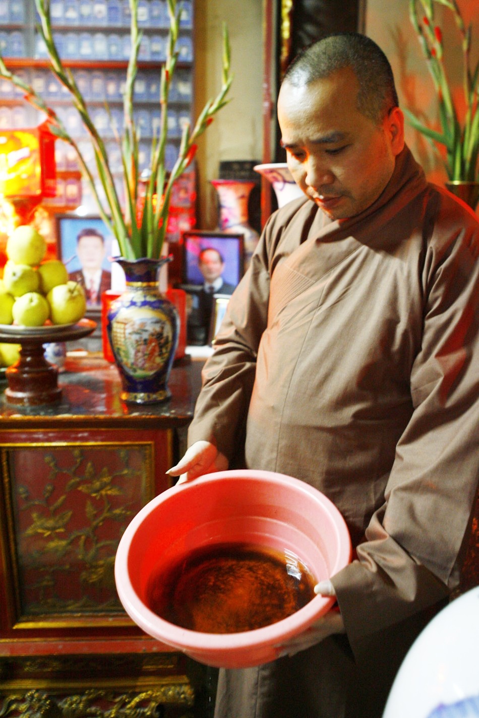 Đại đức Thích Tâm Kiên với chậu hứng nước mưa dột. Ảnh: Hồng Vĩnh Đại đức Thích Tâm Kiên với chậu hứng nước mưa dột. Ảnh: Hồng Vĩnh