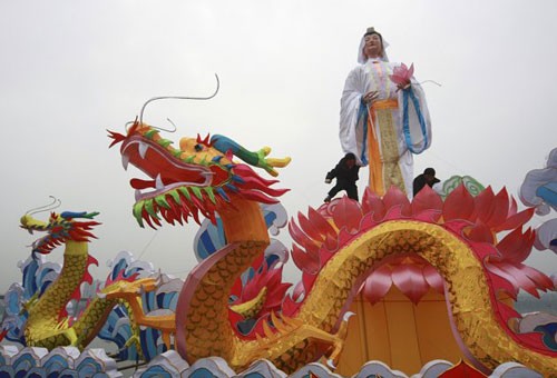 Các công nhân đang lắp đặt đèn lồng khổng lồ hình con rồng trên một hồ nước để chào đón năm mới Âm lịch ở Suining, tỉnh Tứ Xuyên. Năm mới cổ truyền ở Trung Quốc sẽ bắt đầu từ ngày 23/1 Dương lịch. Những người đàn ông Trung Quốc múa rồng trên một hồ nước đóng băng chào đón năm mới ở Shenyang, tỉnh Liêu Ninh ngày 1/1/2012. Thợ lặn múa rồng trong một sự kiện chào đón năm mới Âm lịch ở trong một bể cá tại Bắc Kinh ngày 5/1/2012. Công nhân trang trí một bức tượng hình con rồng để chuẩn bị cho một sự kiện chào đón năm mới cổ truyền ở Ôn Châu, Chiết Giang ngày 9/1. Một công nhân xịt sơn cho bộ phận của chiếc đèn lồng hình người, để chuẩn bị cho một sự kiện chào đón năm mới ở Suining, Tứ Xuyên. Công nhân đang lắp đặt một đèn lồng hình rồng ở trên tường ở Nam Kinh. Du khách chụp hình chiếc đèn lồng hình rồng rực sáng trong đêm ở Bắc Kinh ngày 7/1. Người mẫu đội một chiếc mũ làm từ chocolate, tại sự kiện Chocolate Thế giới ở Thượng Hải để chào đón năm mới. Học sinh cầm câu đối, đèn lồng và múa rồng để chào đóng năm mới tại một ngôi trường tiểu học tại Cửu Giang, Giang Tây. Công nhân nhập cư dùng bữa tại một công trường ở Thành Đô, Trung Quốc ngày 9/1. Hơn 1.400 công nhân nhập cư đã tham gia bữa ăn thường niên để chào mừng năm mới. Đèn lồng trang hoàng rực rỡ tại một con phố ở Zibo, Trung Quốc ngày 8/1. Công nhân đang dựng một bức tượng hình Quan Âm trên những chiếc đèn lồng hình rồng ở Tứ Xuyên ngày 7/1. Một giáo viên đang cho các học sinh xem bức tranh hình rồng ở một ngôi trường tiểu học tại tỉnh Sơn Đông ngày 5/1. Người đàn ông giơ bức thư có gắn tem hình rồng tại Huaibei, tỉnh An Huy ngày 5/1. Tem thư được thiết kế có hình rồng này đã gây ra sự chỉ trích của người dân, khi họ cho rằng con rồng này có hình dáng quá hung tợn.